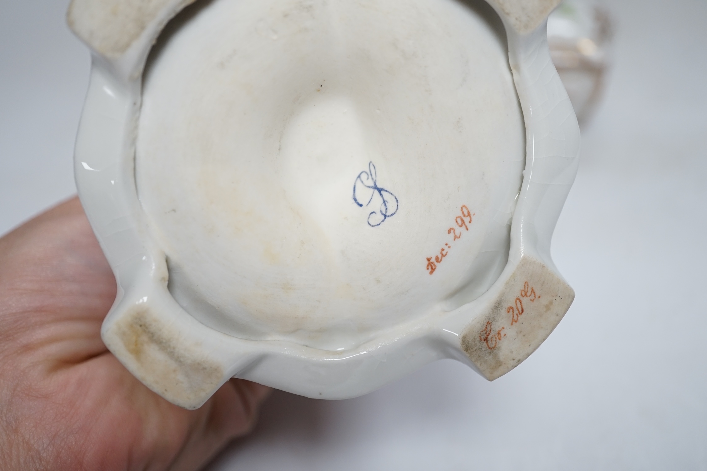 A porcelain shell-shaped centrepiece, a Dresden pill box, a pair of taper holders and a porcelain figure, tallest 21cm
